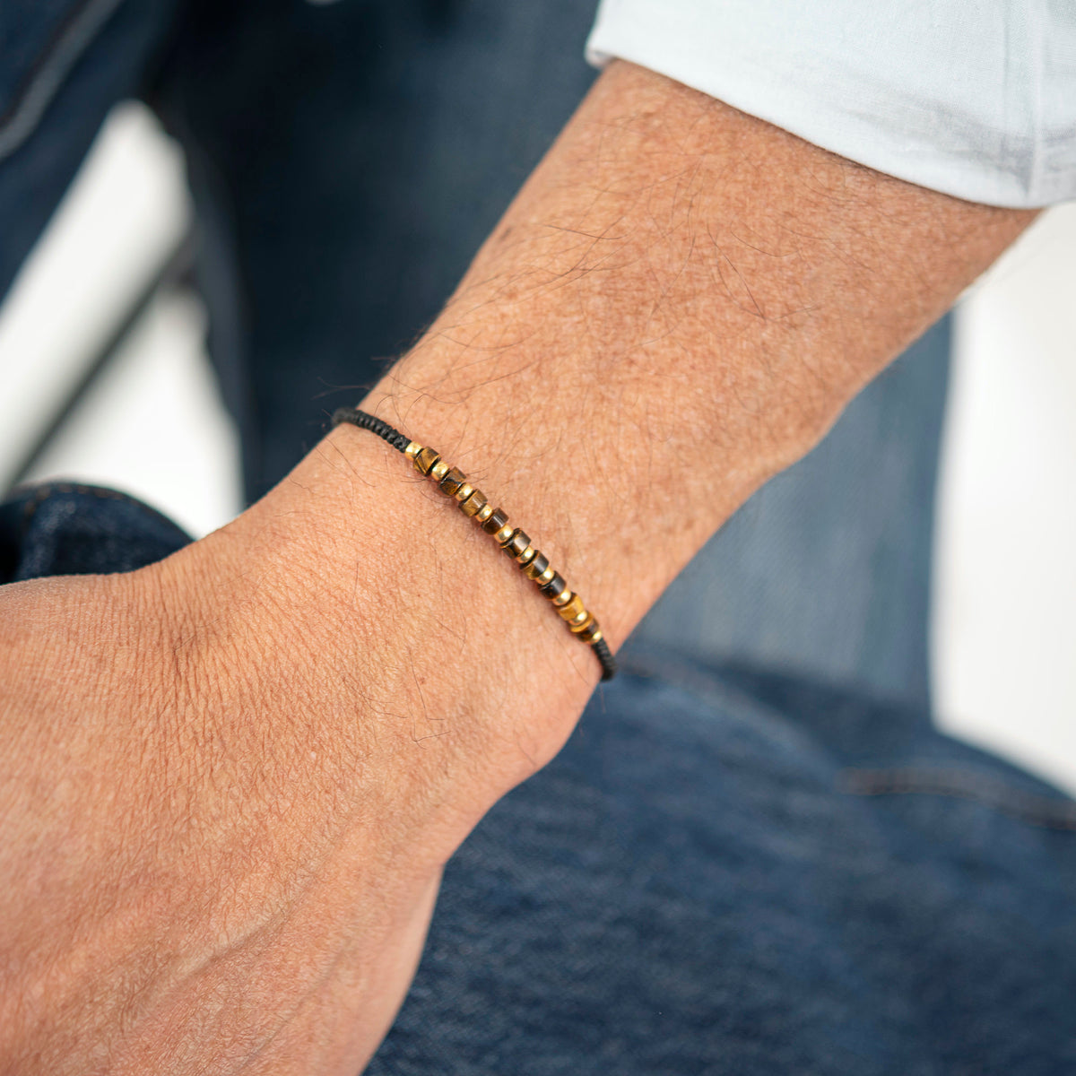 Lifestyle image of tiger eye and Miyuki bead bracelet for men with adjustable black wax cord, handmade minimalist bracelet.