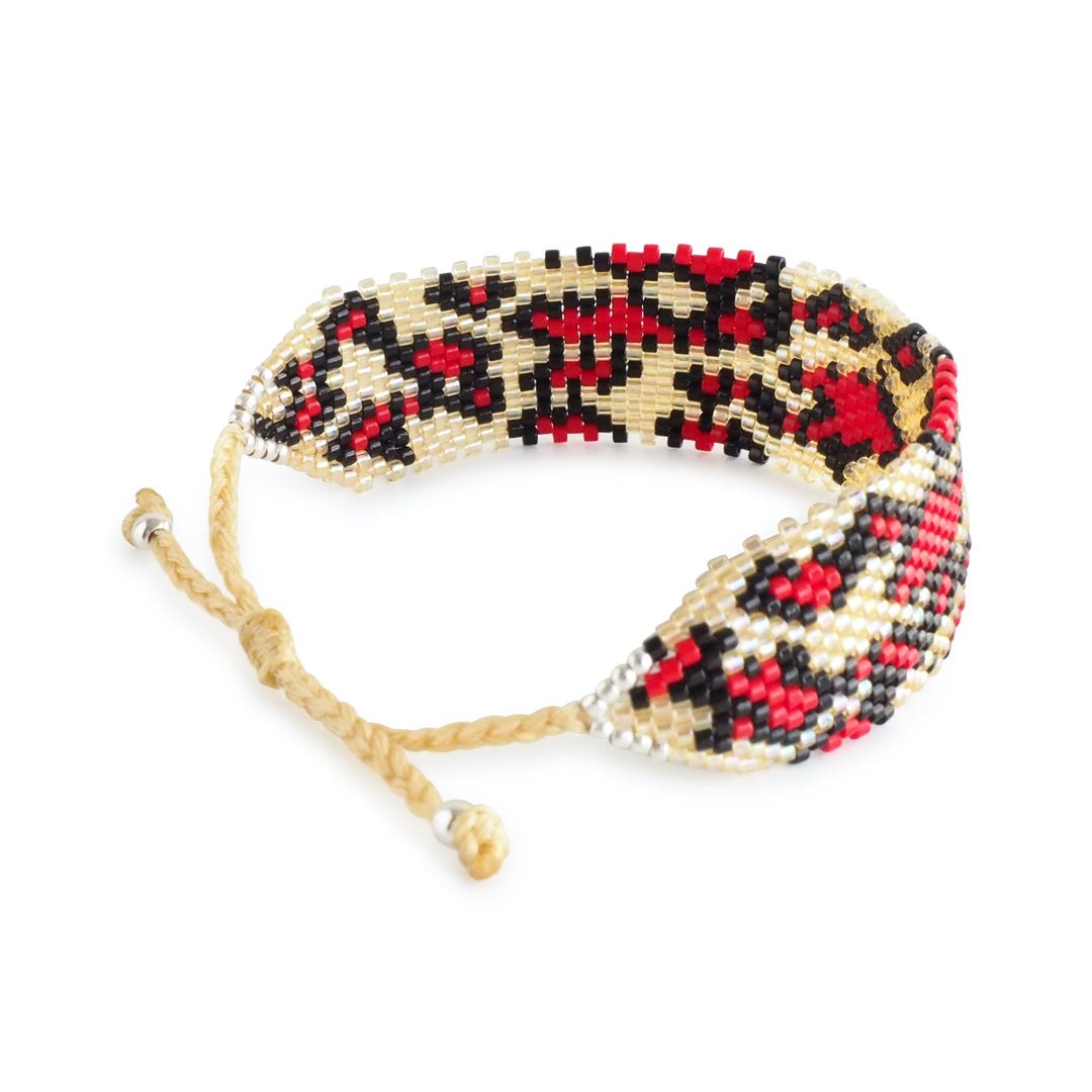 Red and black animal print Miyuki bead bracelet with gold accents, handcrafted by Colombian artisans, bold statement jewelry cuff.