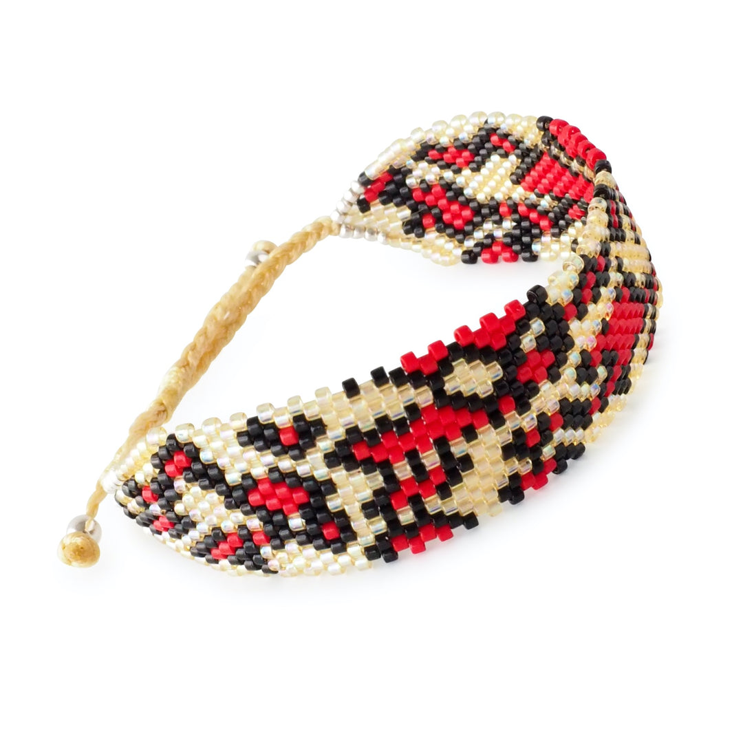 Red and black animal print Miyuki bead bracelet with gold accents, handcrafted by Colombian artisans, bold statement jewelry cuff.